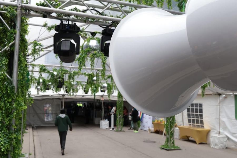 White Air Motion horn in the foreground of a tent lined with greenery and moving head lights