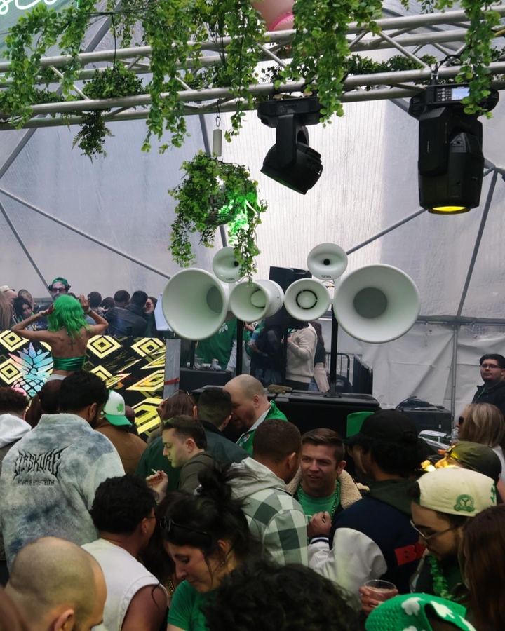 Crowd in green under Air Motion horns and moving lights inside a tent