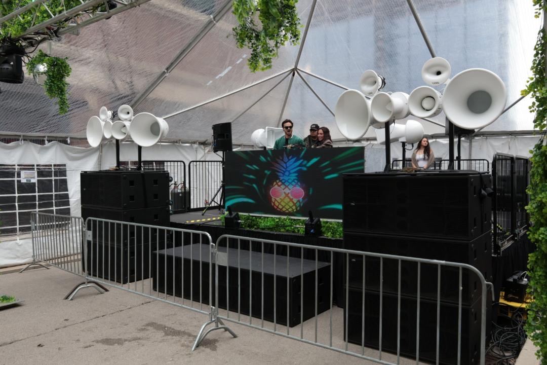 Two stacks of Stasys XV2 subs with Air Motion tops flanking a DJ booth and LED wall inside a tent